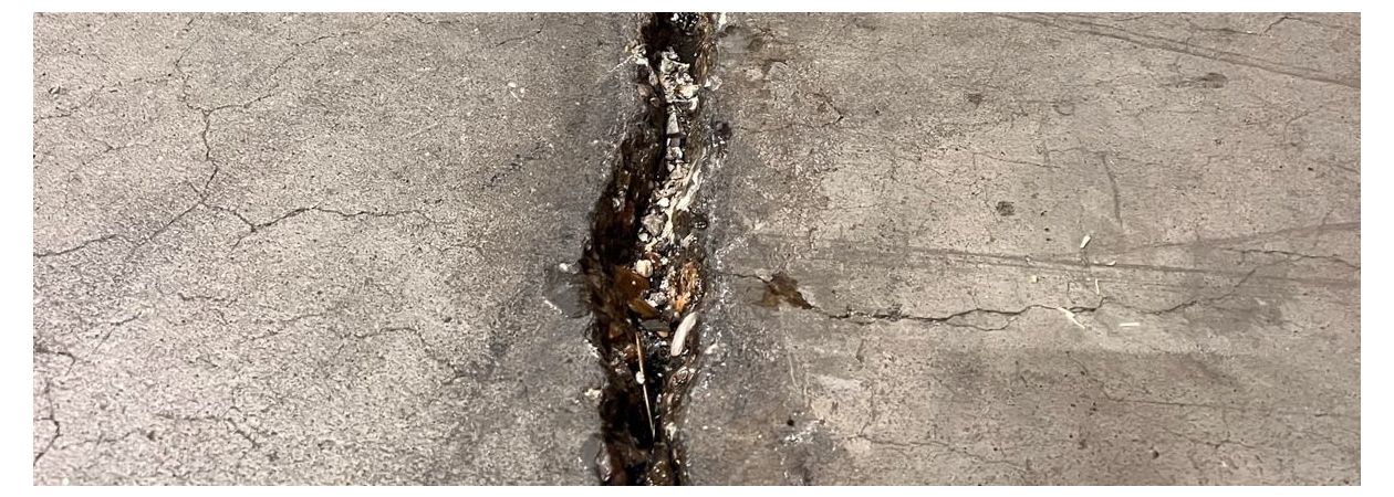 Een betonvloer met een grote scheur welke gerepareerd moet worden.