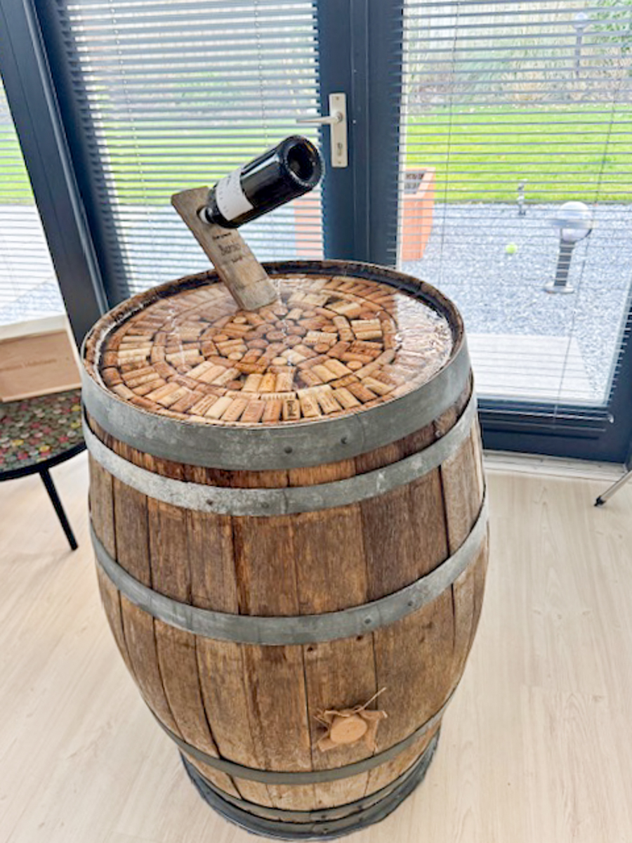 Een wijnvat welke rechtop staat, in de bovenkant van het wijnvat zitten er wijnkurken in de epoxy ingegoten.